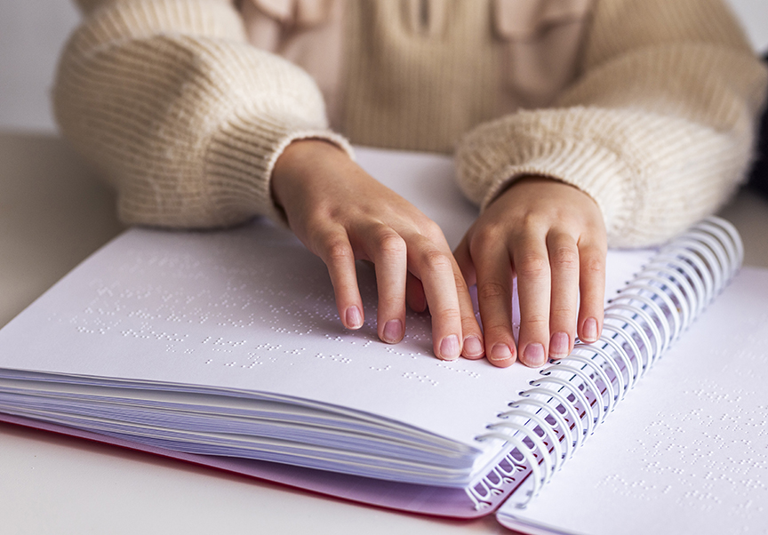 Händer som läser punktskrift i en bok