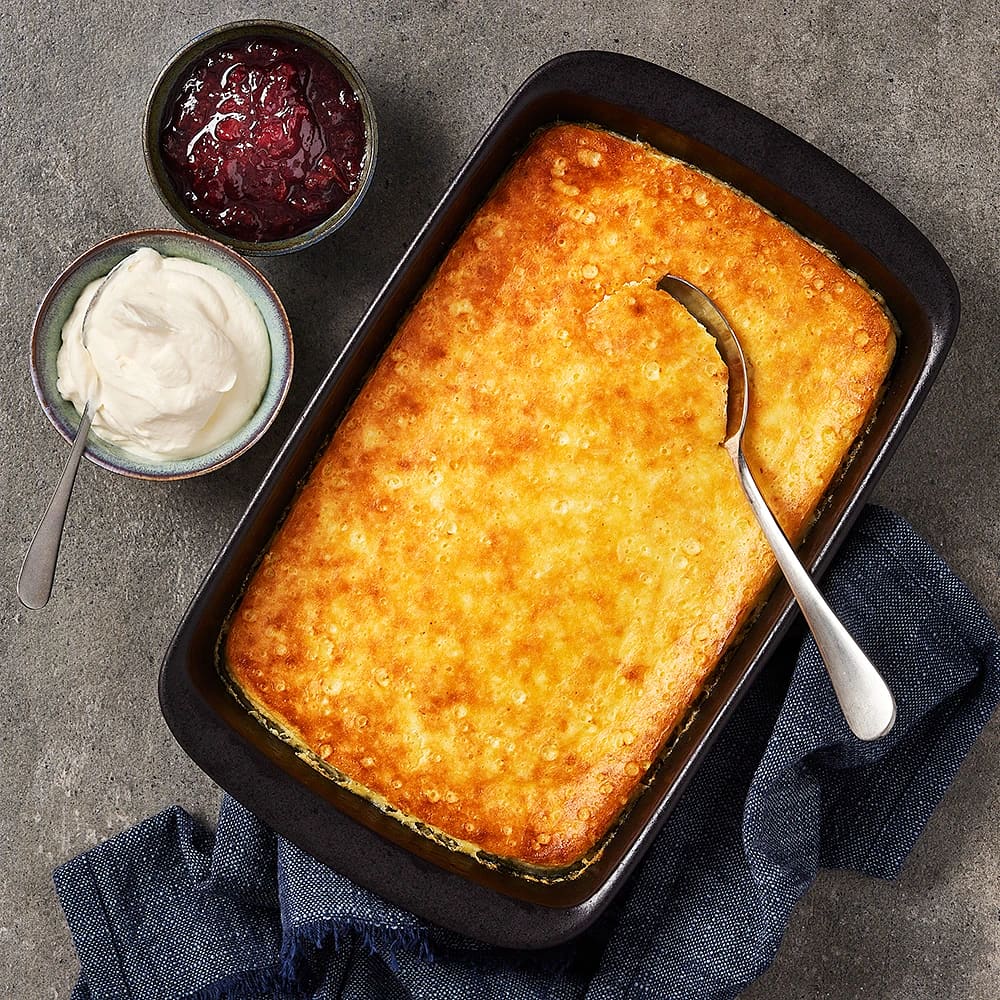Finare ostkaka i glasform, här syns även en skål med vispad grädde och en annan med sylt